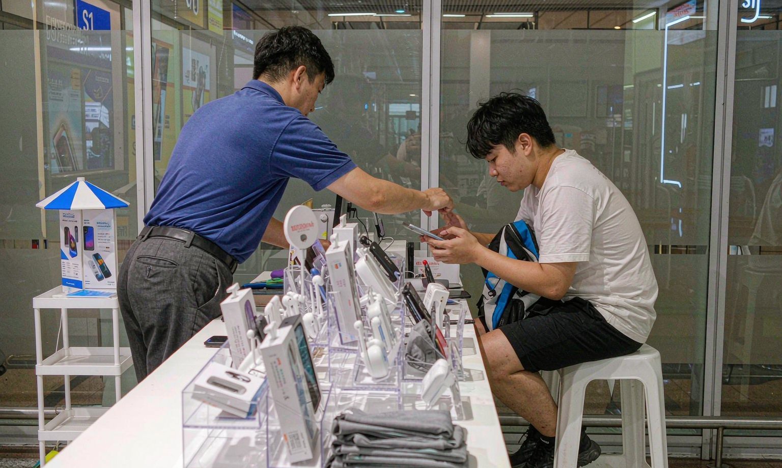 機場電信櫃台人員協助旅客設定 SIM 卡,漫遊日租是最省事的路線